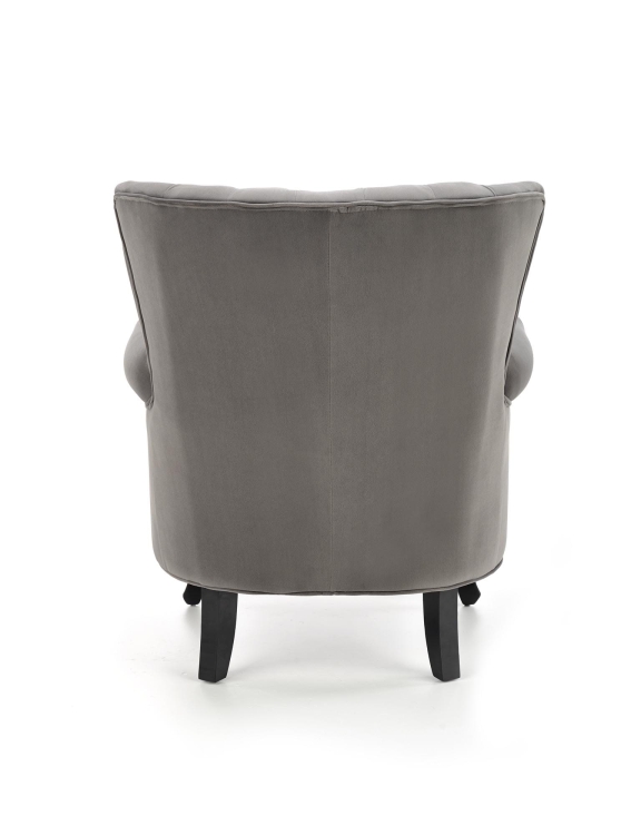 Stylowy fotel welurowy TITAN w eleganckim wnętrzu z dekoracyjnymi nitami, profilowanymi podłokietnikami i solidną drewnianą podstawą, nawiązujący do trendu fotel welurowy do salonu.